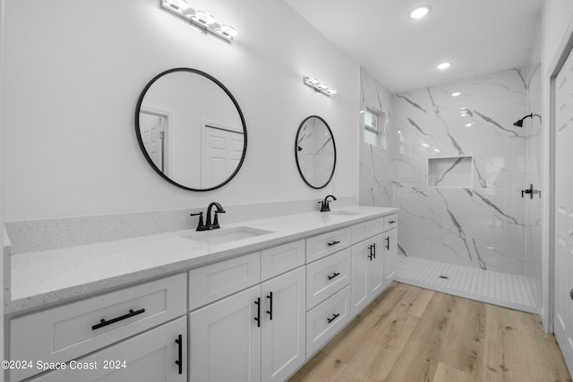 full bath featuring a marble finish shower, recessed lighting, double vanity, and a sink