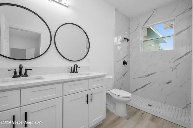 bathroom with double vanity, toilet, a marble finish shower, and a sink