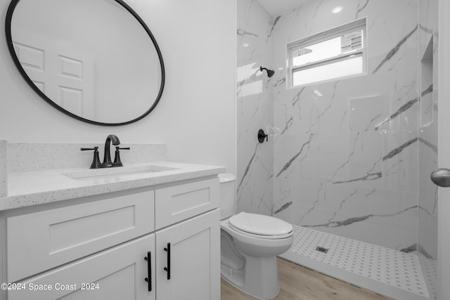 full bath with vanity, toilet, a marble finish shower, and wood finished floors