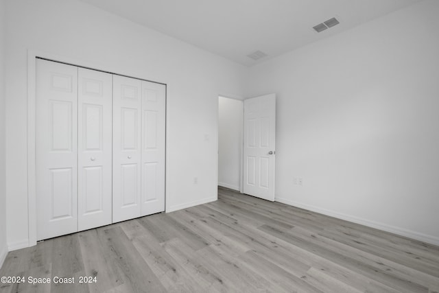 unfurnished bedroom featuring baseboards, a closet, visible vents, and wood finished floors