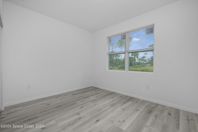 spare room with baseboards and wood finished floors