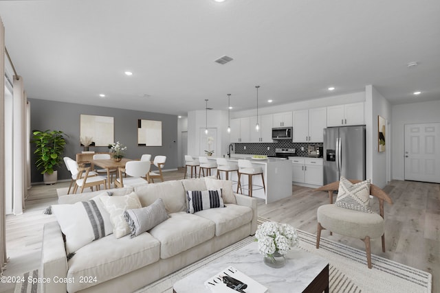 living area featuring light wood finished floors, visible vents, baseboards, and recessed lighting