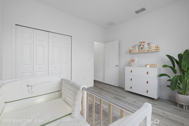 bedroom featuring baseboards, a closet, visible vents, and wood finished floors
