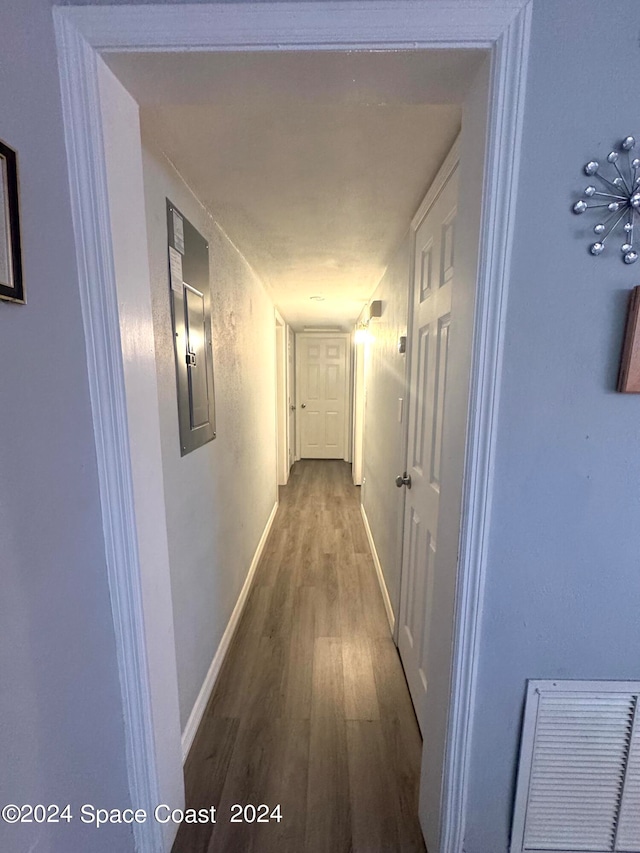 corridor with hardwood / wood-style floors and electric panel