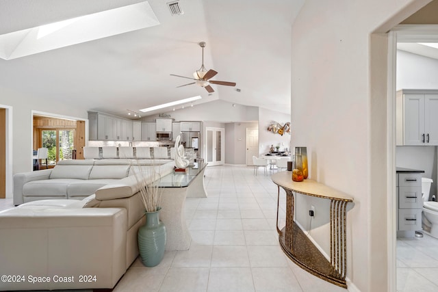 tiled living room featuring ceiling fan and lofted ceiling with skylight