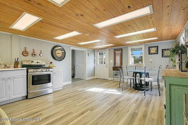 kitchen with wood ceiling, wooden walls, white cabinetry, stainless steel range oven, and light hardwood / wood-style floors