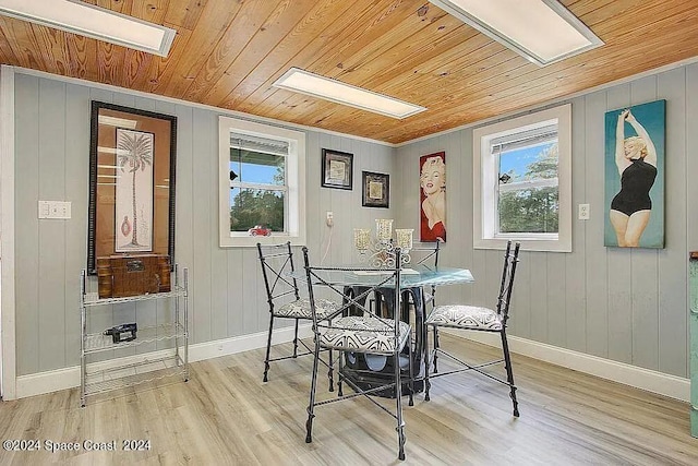 dining space featuring a skylight, wooden walls, light wood-type flooring, and wooden ceiling