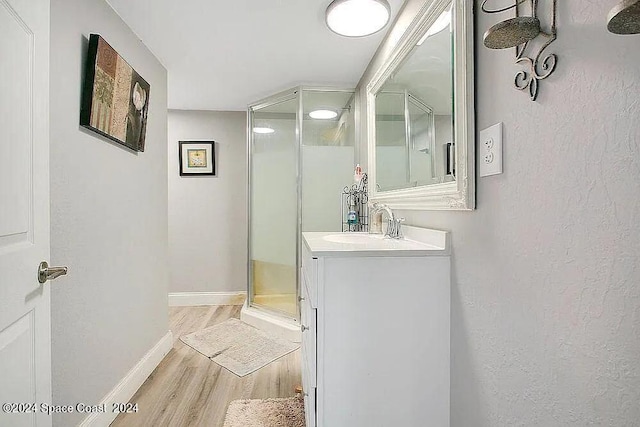 bathroom with hardwood / wood-style floors, walk in shower, and vanity