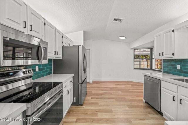 kitchen featuring a textured ceiling, appliances with stainless steel finishes, backsplash, and white cabinetry