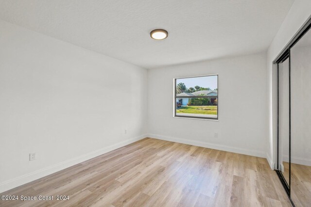 unfurnished bedroom with a textured ceiling, light wood-type flooring, and a closet