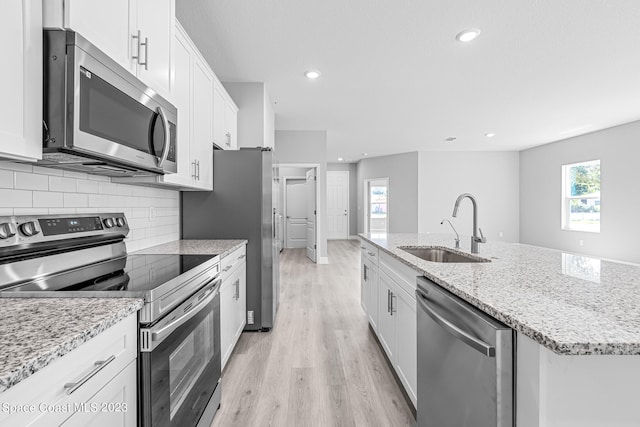 kitchen featuring appliances with stainless steel finishes, a kitchen island with sink, white cabinetry, and sink