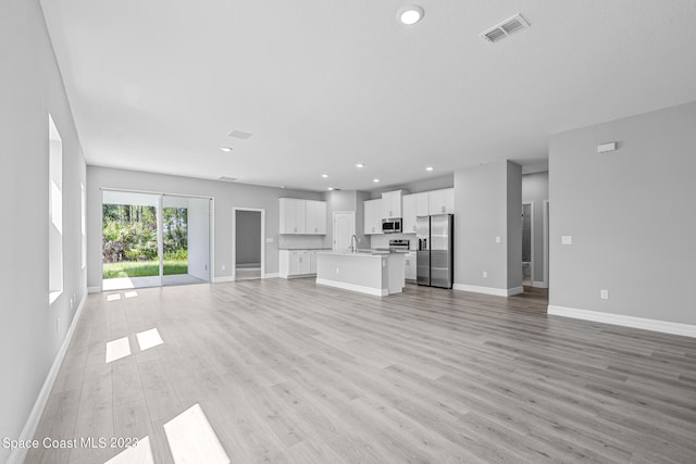 unfurnished living room with light hardwood / wood-style floors and sink