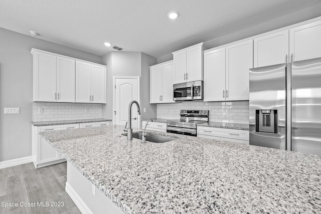 kitchen with light hardwood / wood-style floors, sink, white cabinets, appliances with stainless steel finishes, and light stone countertops