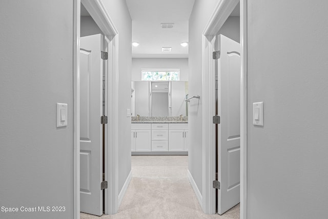 hall featuring light colored carpet and sink