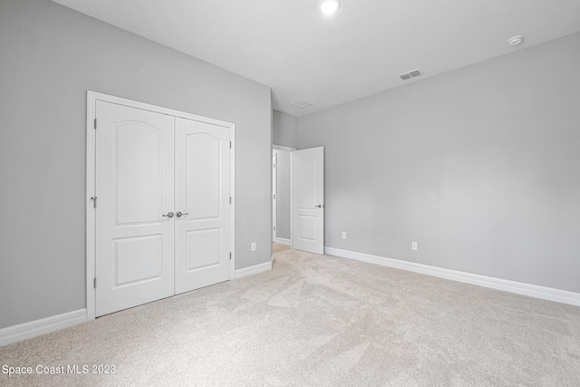 unfurnished bedroom with a closet and light colored carpet