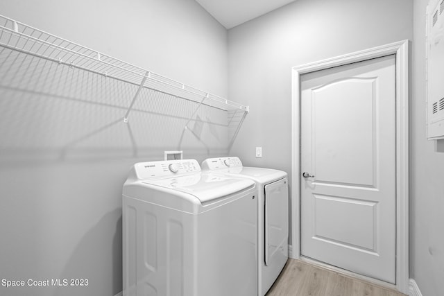 clothes washing area with light wood-type flooring and independent washer and dryer