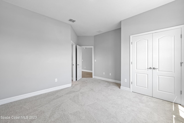 unfurnished bedroom with light carpet and a closet