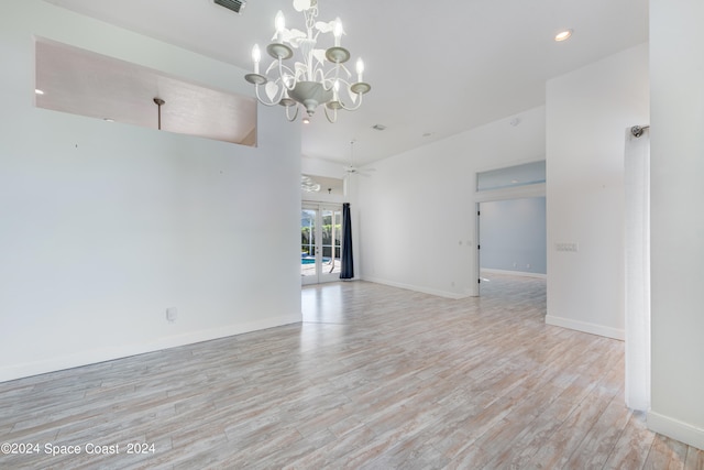 empty room featuring ceiling fan with notable chandelier and light wood-type flooring