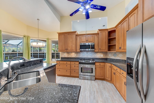 kitchen featuring light wood-type flooring, decorative backsplash, sink, appliances with stainless steel finishes, and decorative light fixtures