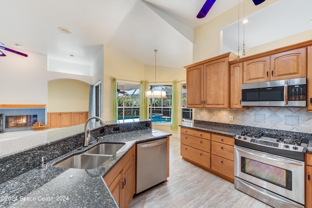 kitchen featuring light hardwood / wood-style floors, dark stone countertops, decorative light fixtures, sink, and stainless steel appliances