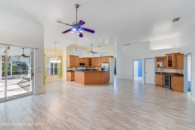 kitchen featuring stainless steel appliances, beverage cooler, light hardwood / wood-style floors, a high ceiling, and hanging light fixtures