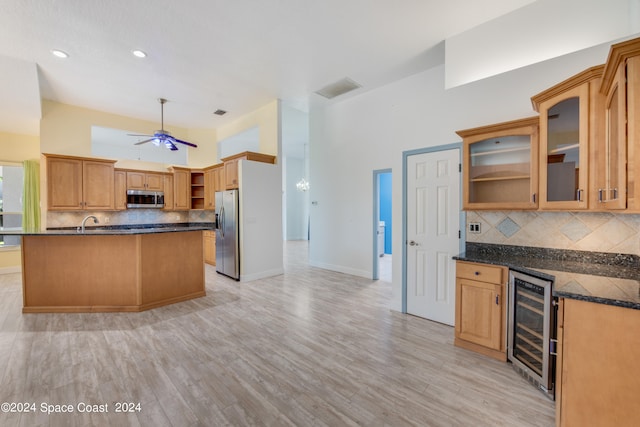 kitchen with wine cooler, appliances with stainless steel finishes, backsplash, and light hardwood / wood-style floors