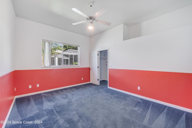 unfurnished room with ceiling fan and dark carpet