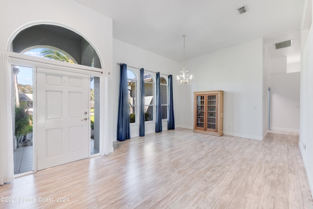 foyer entrance with a high ceiling, light wood-type flooring, and a chandelier