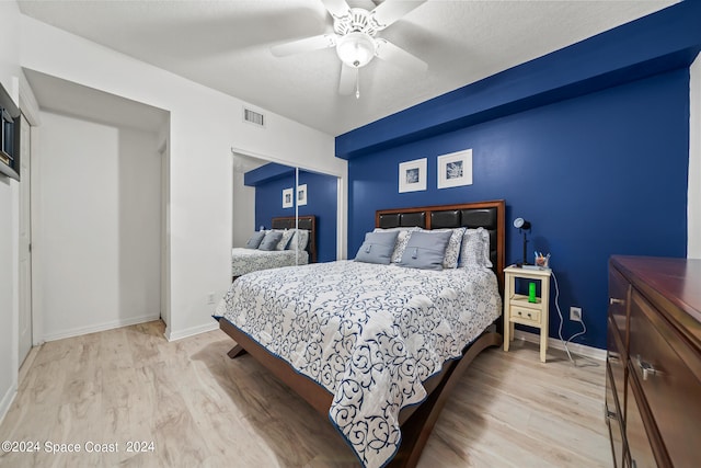 bedroom with a closet, light hardwood / wood-style floors, and ceiling fan