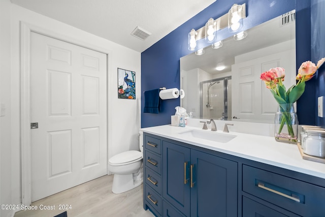 bathroom featuring hardwood / wood-style floors, vanity, toilet, and an enclosed shower