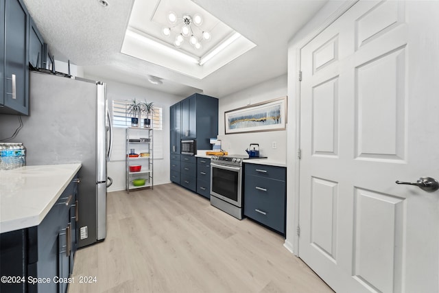 kitchen featuring blue cabinets, a textured ceiling, stainless steel appliances, and light hardwood / wood-style flooring