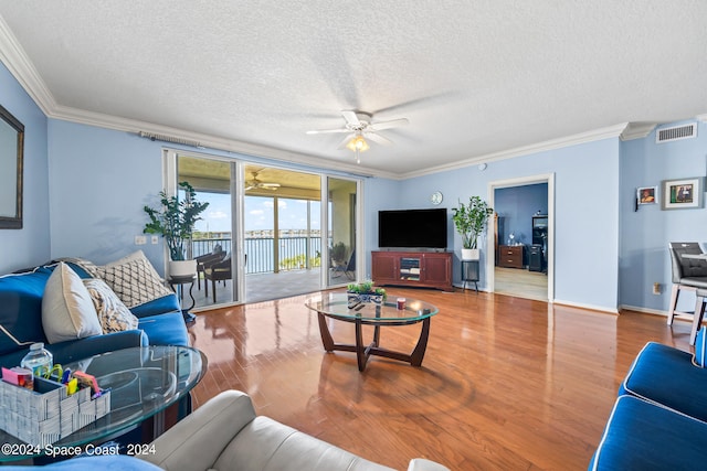 living room featuring ornamental molding, ceiling fan, hardwood / wood-style flooring, and a textured ceiling