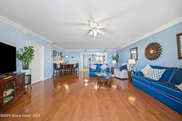 living room with a textured ceiling, ornamental molding, hardwood / wood-style floors, and ceiling fan