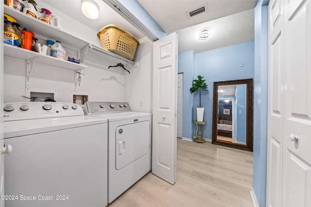 laundry area featuring light hardwood / wood-style floors, separate washer and dryer, and a textured ceiling