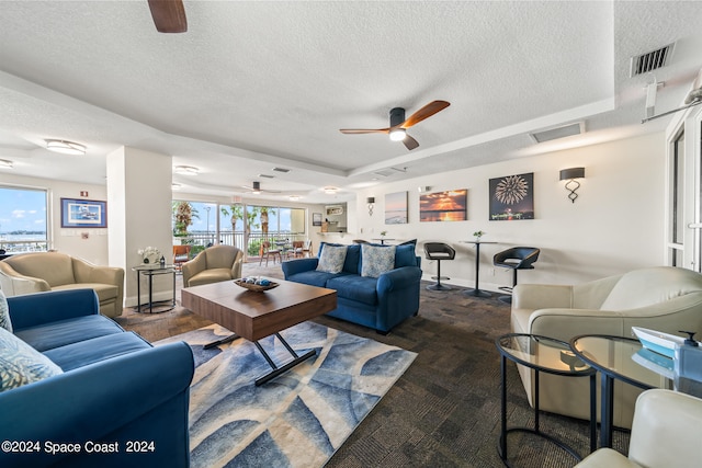 living room featuring ceiling fan and a textured ceiling