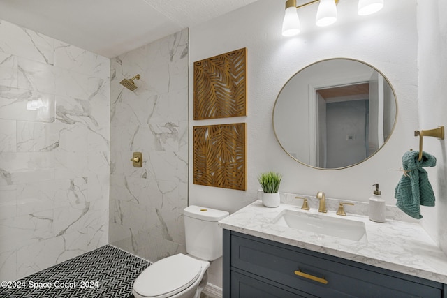 bathroom with tiled shower, vanity, and toilet