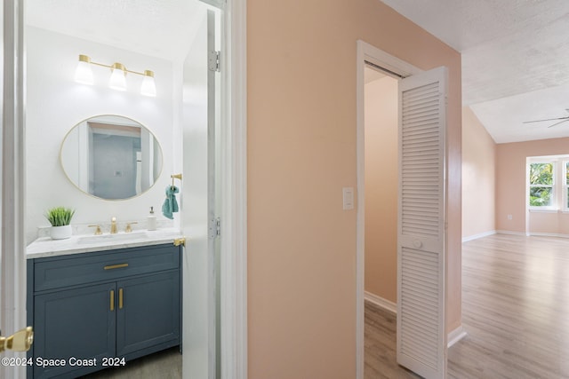 bathroom with vanity, lofted ceiling, hardwood / wood-style flooring, ceiling fan, and a textured ceiling