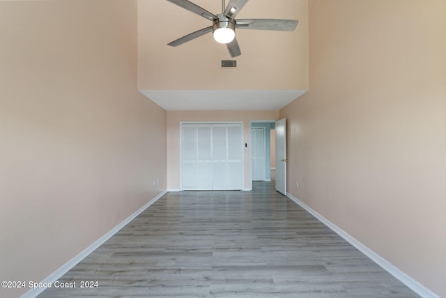 corridor featuring a towering ceiling and light wood-type flooring