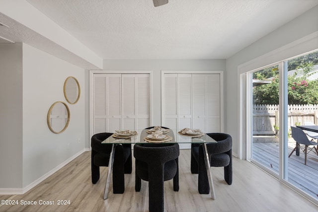 dining area with a textured ceiling and light hardwood / wood-style flooring