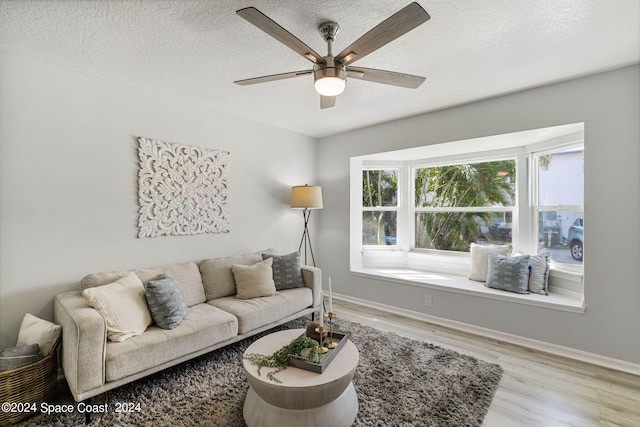 living room featuring ceiling fan, a textured ceiling, and light hardwood / wood-style flooring