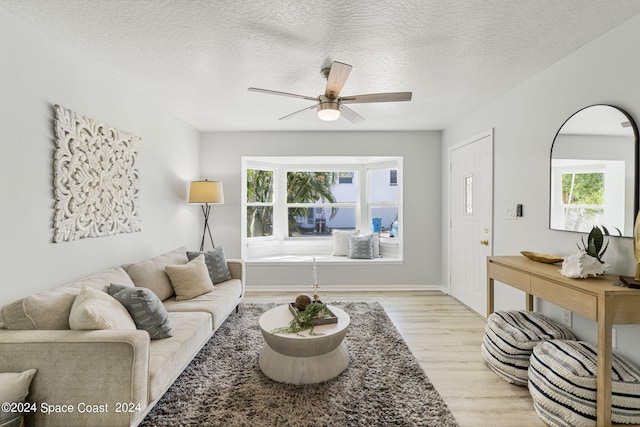 living room featuring a textured ceiling, light hardwood / wood-style flooring, and ceiling fan