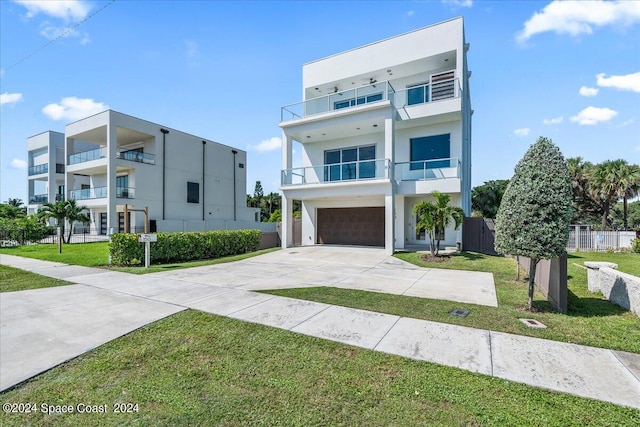 contemporary house with a garage, a front yard, and a balcony