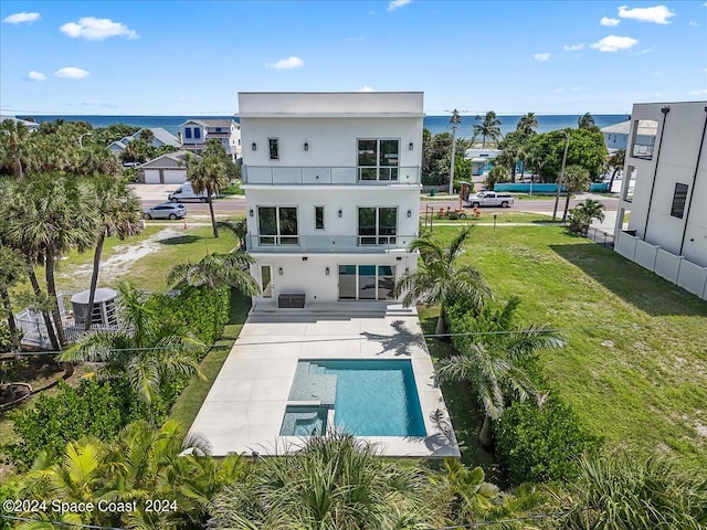 rear view of house featuring a patio area, a lawn, a balcony, and a water view