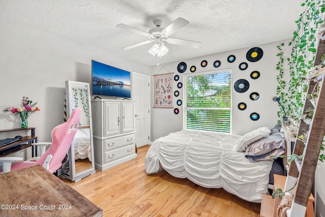 bedroom with a textured ceiling, light hardwood / wood-style floors, and ceiling fan