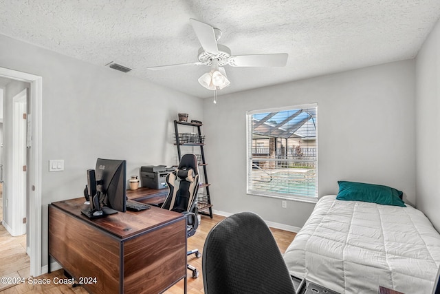 bedroom featuring a textured ceiling, light hardwood / wood-style floors, and ceiling fan