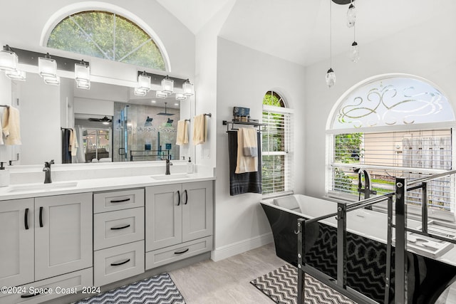 bathroom featuring vaulted ceiling, vanity, independent shower and bath, wood-type flooring, and ceiling fan