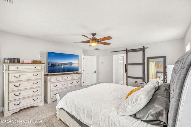 bedroom featuring a barn door, a textured ceiling, light carpet, and ceiling fan