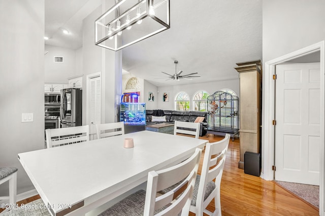 dining space featuring ceiling fan, light hardwood / wood-style flooring, and vaulted ceiling