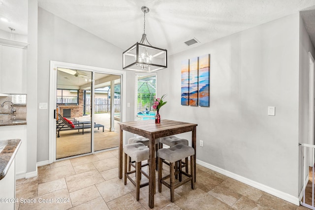 dining space with vaulted ceiling, a textured ceiling, sink, and a chandelier