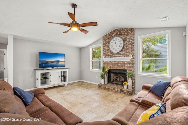 living room featuring lofted ceiling, ceiling fan, a fireplace, and a healthy amount of sunlight